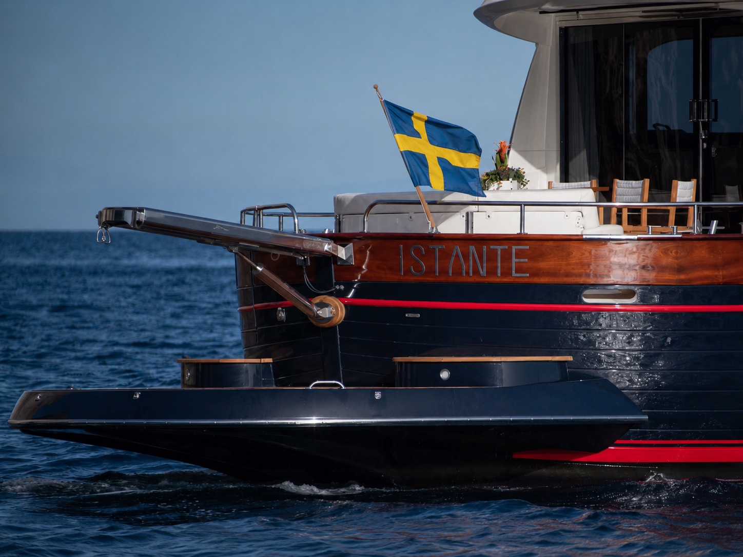 Båtens akter med namnet Istante och svensk flagga på öppet hav