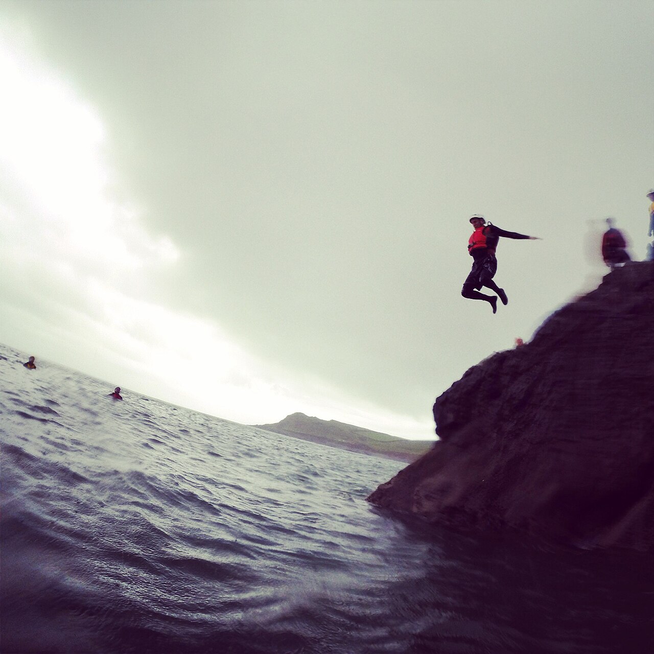 Person som hoppar från en klippa ner i havet med flytväst